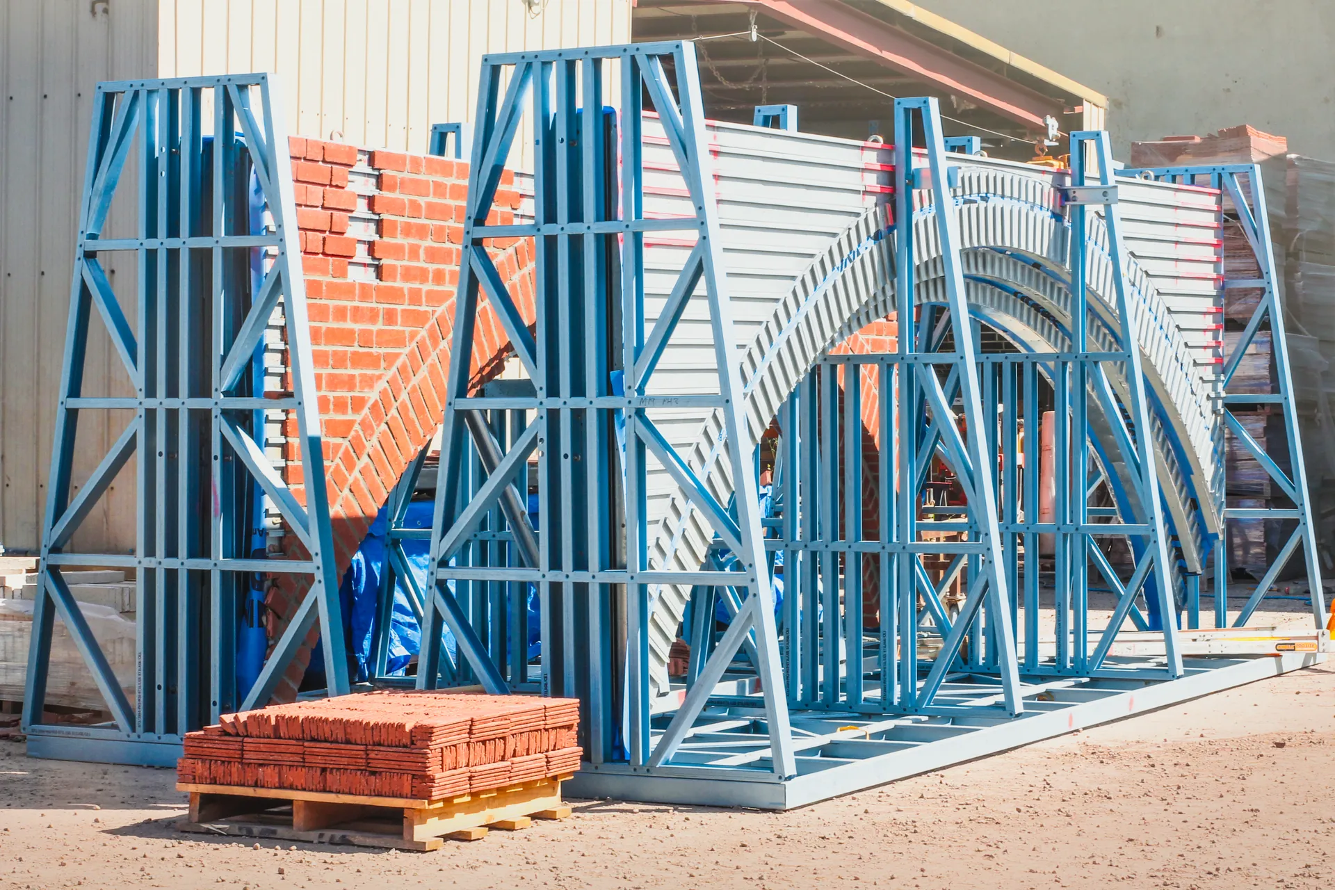 Prefabricated steel arch frame with real brick facings partially installed, before and after